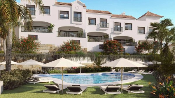 Het gemeenschappelijke zwembad omringd door palmbomen in een townhouse complex in Estepona, Costa del Sol.