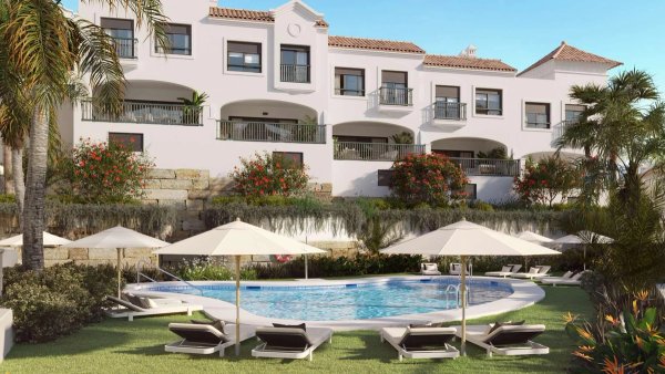 Het gemeenschappelijke zwembad omringd door palmbomen in een townhouse complex in Estepona, Costa del Sol.