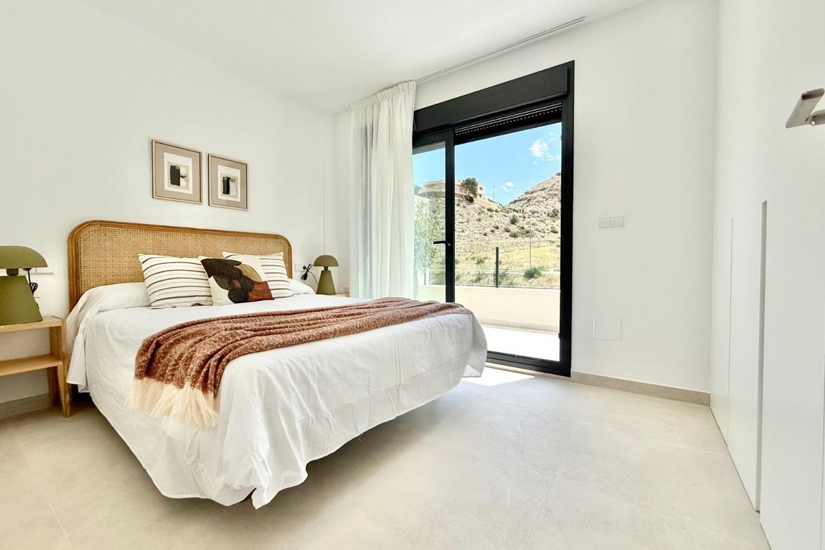 Heldere master slaapkamer met een bed en groot raam met uitzicht op de bergen in een town house in Cox, Costa Blanca.