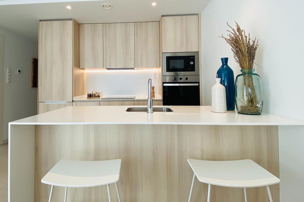 Moderne keuken met lichte houten kasten en witte werkbladen in een 3-slaapkamer bungalow, Pilar de La Horadada.