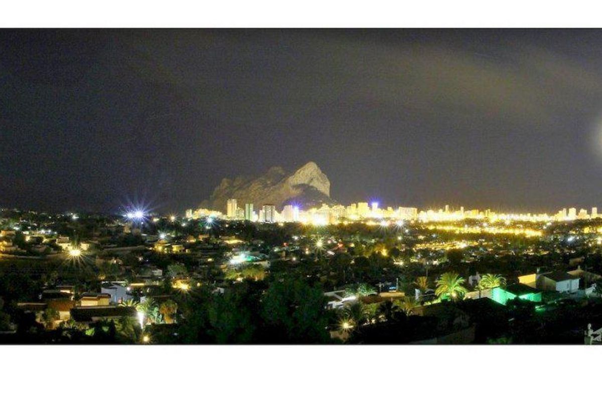 Nachttijd panoramisch uitzicht op Calpe verlicht met lichten en de maan in Costa Blanca Noord.
