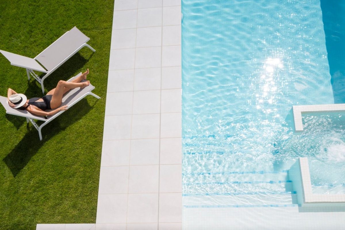Relaxing by the pool, enjoying sunshine, with a luxurious pool area in Baños y Mendigo villa.