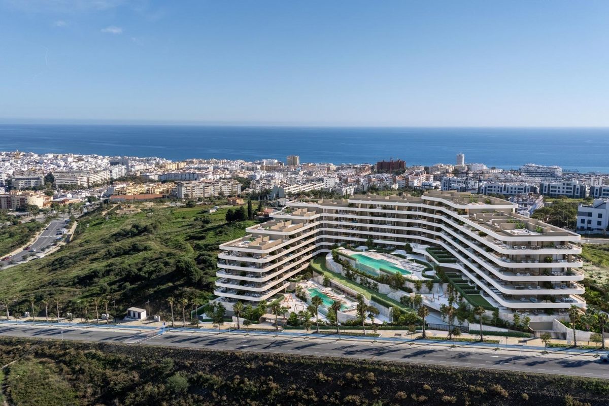 Luchtfoto van het appartementencomplex in Estepona, met het schilderachtige kustlijn en zwembaden.