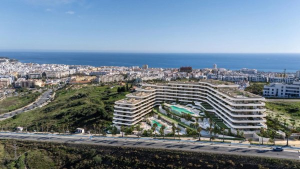 Luchtfoto van een modern appartementencomplex in Estepona met uitzicht op de oceaan en een zwembad.