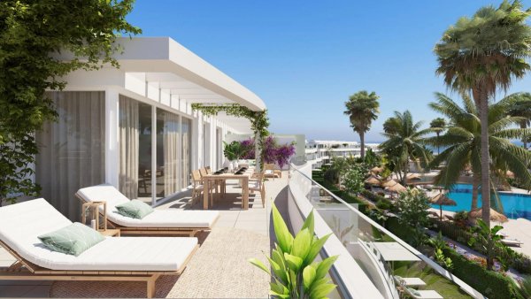 Ruim terras met ligbedden en tropische planten bij een 3-slaapkamer appartement in San Roque, Costa del Sol.