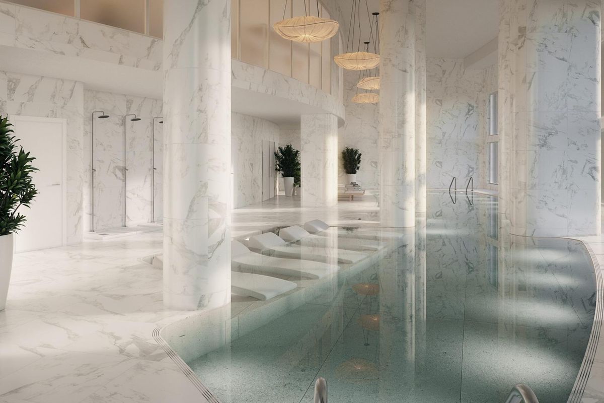 Heldere binnenzwembad met marmeren accenten en comfortabele ligstoelen, in een appartement in Málaga, Costa del Sol.