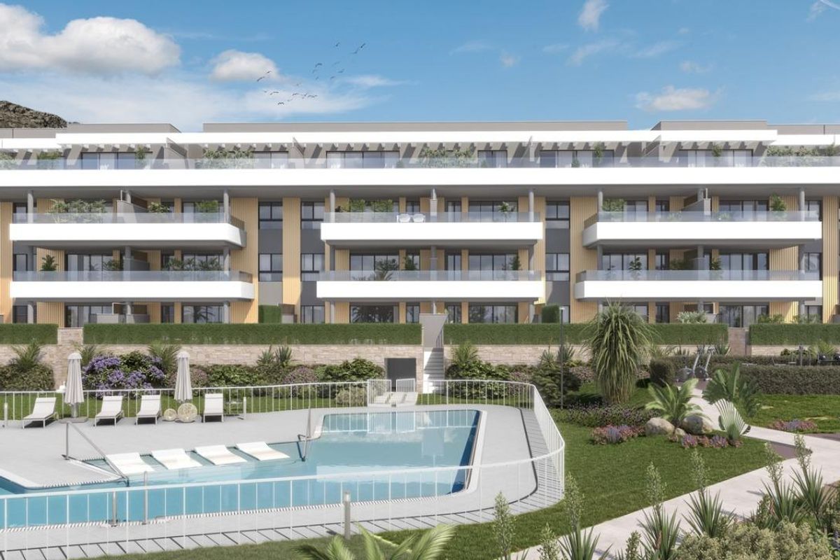 Breedbeeld van het stijlvolle appartementgebouw in Torremolinos, met tuinen en zwembadgebied.