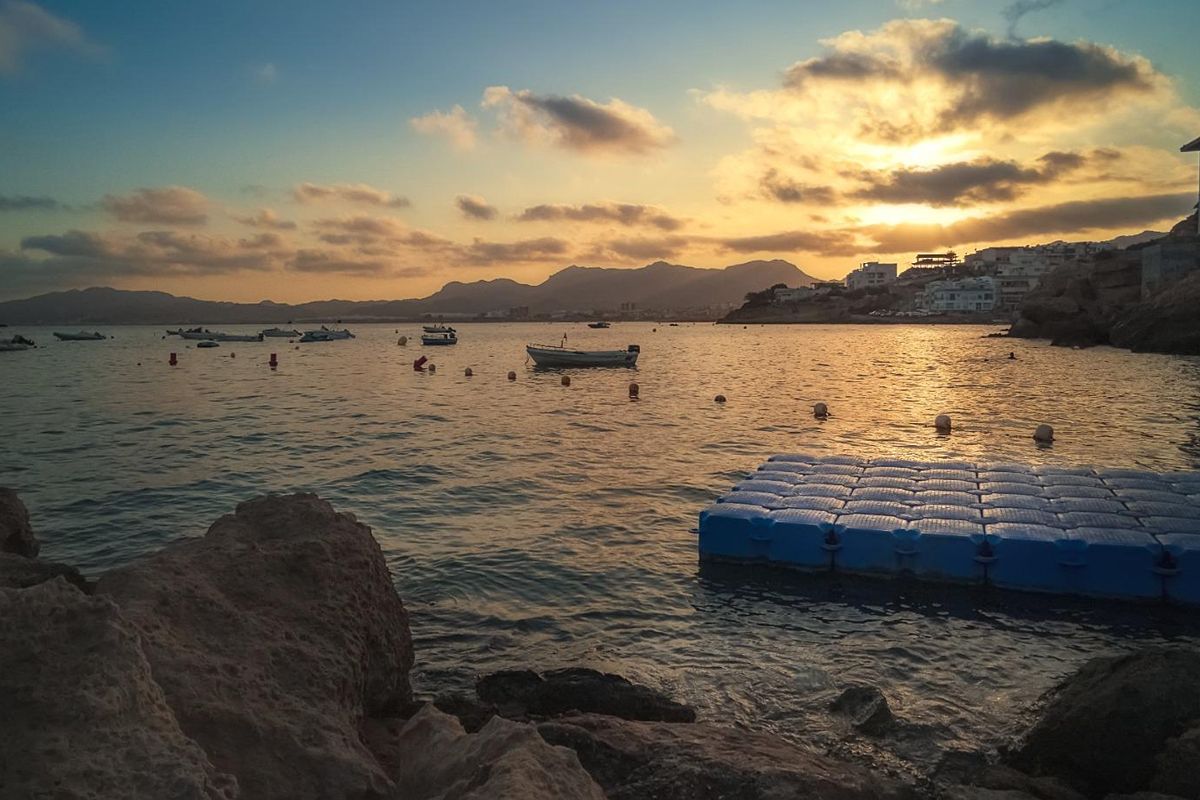 Serene zonsondergang uitzicht over de baai in San Juan de los Terreros, met boten op het water.