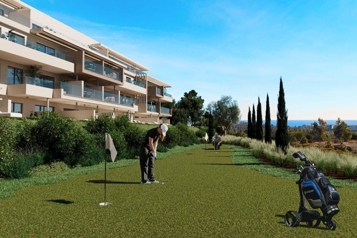 Golf putting green met spelers die van de zon genieten, vlakbij een modern appartementencomplex in Mijas, Costa del Sol.