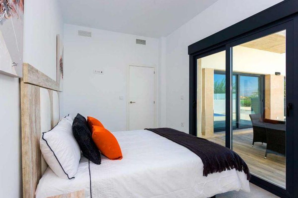 Heldere slaapkamer in een bungalow in Daya Nueva, met uitzicht op het zwembad en stijlvolle meubels voor comfort.