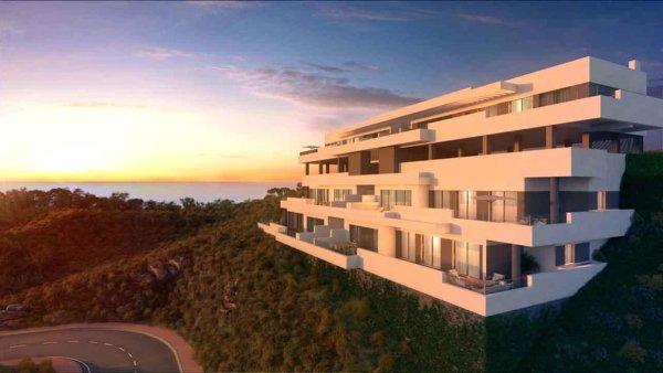 Modern appartementencomplex in Mijas, Costa del Sol, met uitzicht op de kust bij zonsondergang.