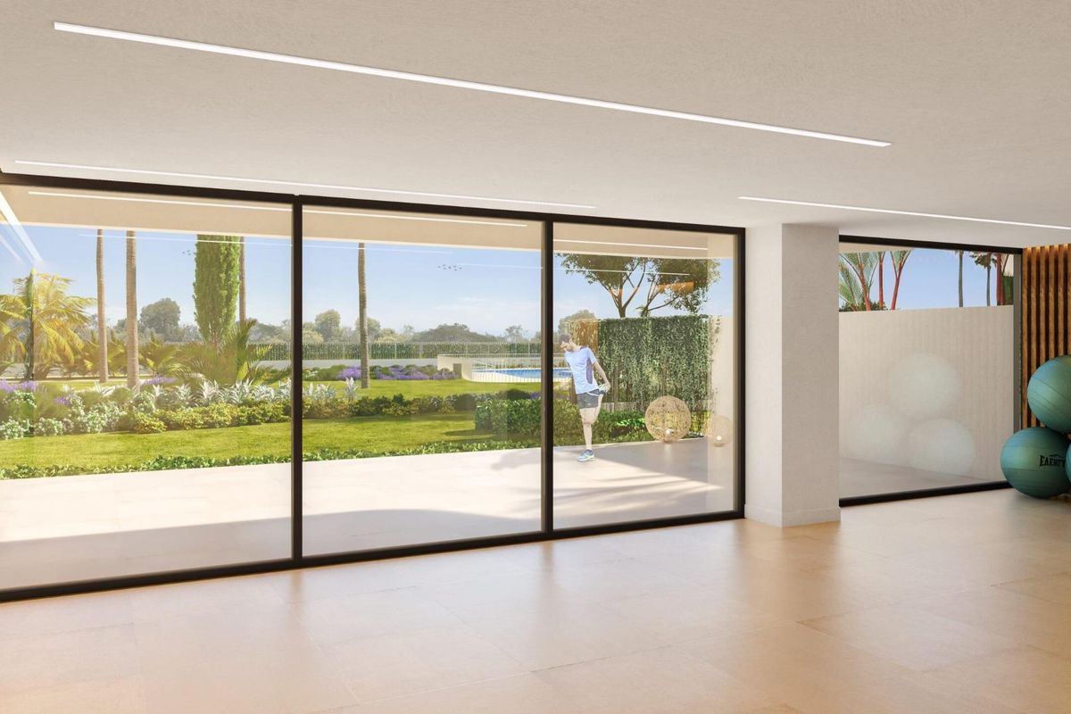 Heldere binnenruimte met grote ramen met uitzicht op de tuin in Torremolinos, Costa del Sol.
