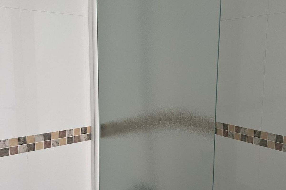 Douchehoek in een badkamer van een penthouse in Calpe, met glazen douchewand en betegelde muren.