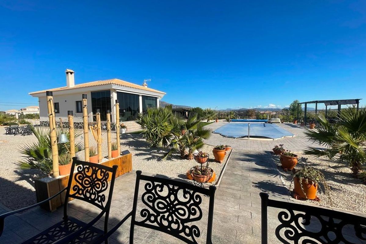 Buitenruimte van een villa met zwembad en zitgedeelte, omringd door tuinen in Pinoso, Costa Blanca Zuid, Spanje.