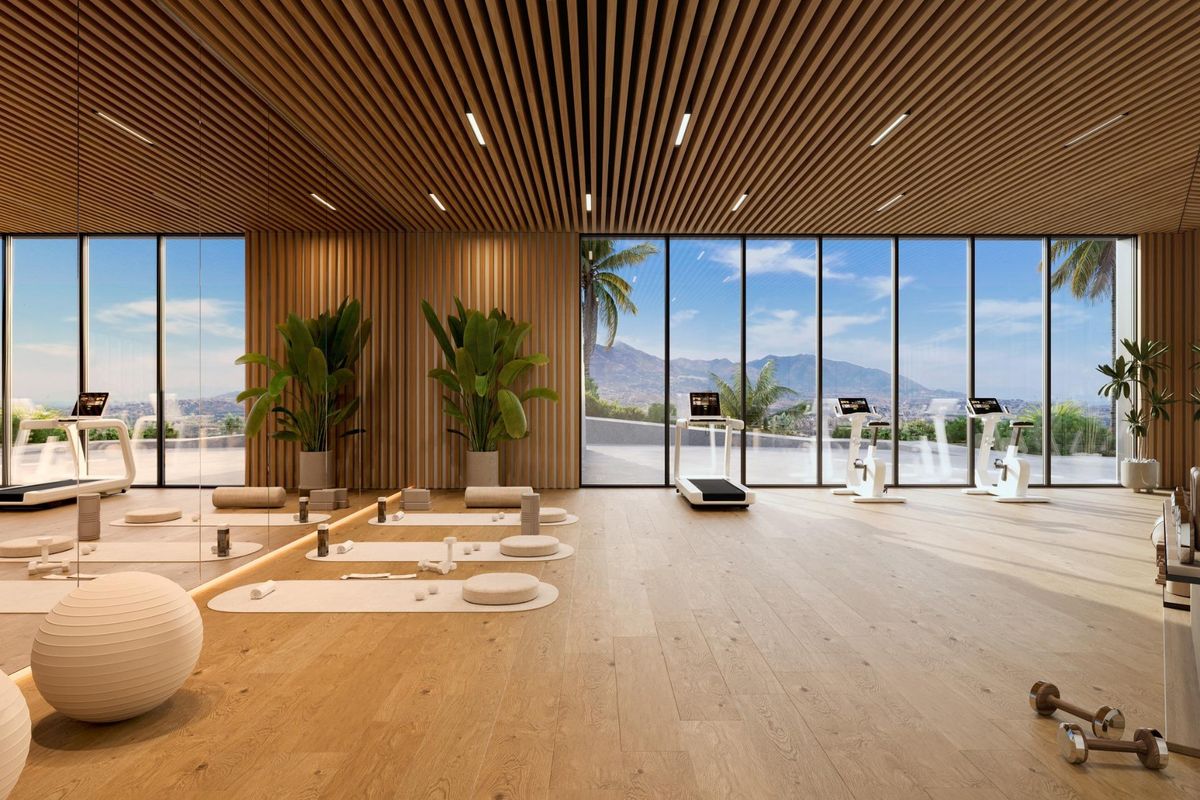 Lichte fitnessruimte met houten vloer, ramen van vloer tot plafond, bergzicht en moderne fitnessapparatuur