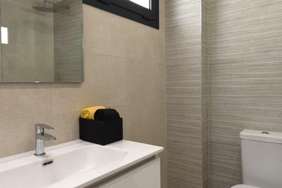 Modern badkamer in het penthouse met strakke armaturen en elegante tegels in San Miguel de Salinas.