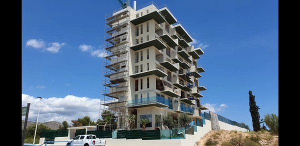 Buitenkant van een modern 1-slaapkamer appartement gebouw in Finestrat, Costa Blanca. Onder constructie met steiger.