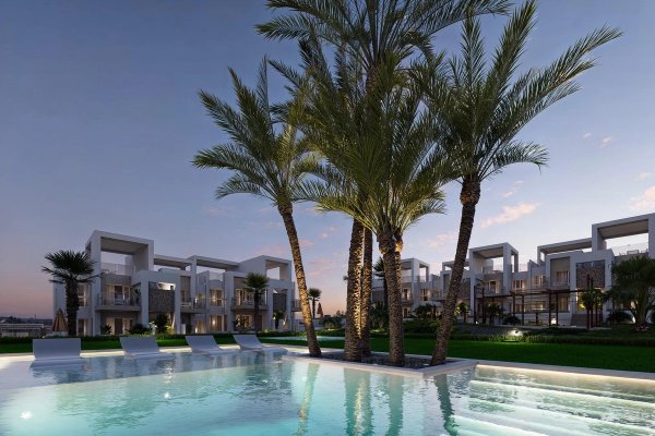 Avondbeeld van een modern bungalowcomplex met palmbomen en een zwembad in Ciudad Quesada, Costa Blanca.