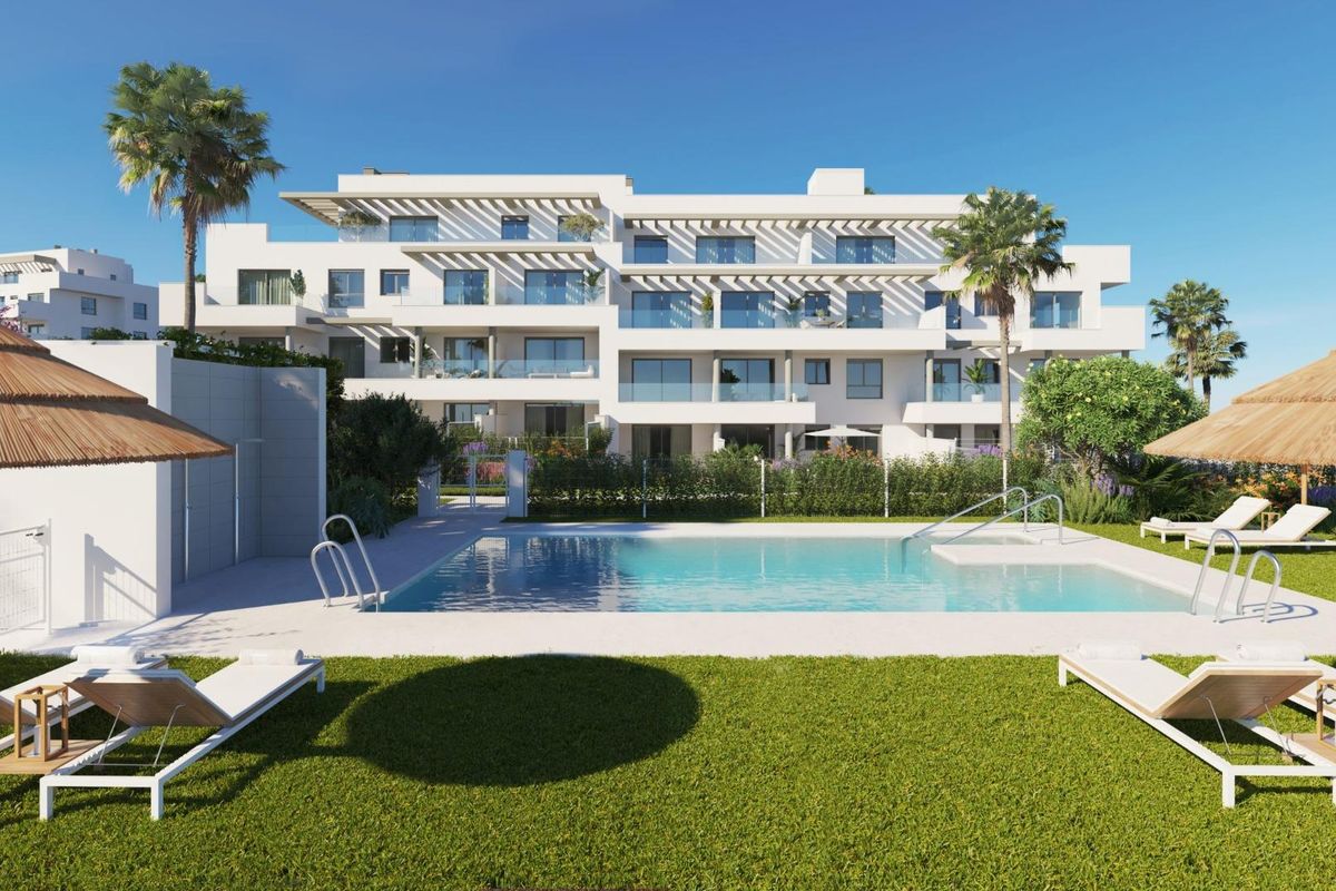 Modern wit appartementencomplex met zwembad in Mijas, Costa del Sol, met palmbomen en ligbedden