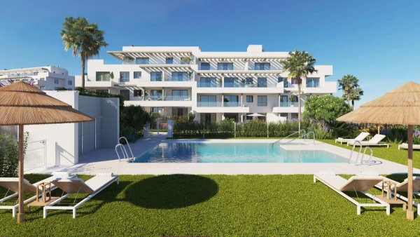 Modern wit appartementencomplex met zwembad in Mijas, Costa del Sol, met palmbomen en ligbedden