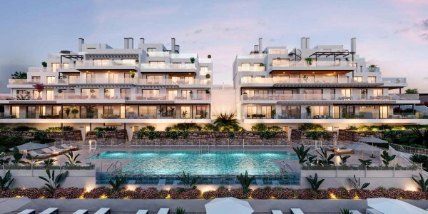Buitenzijde van een modern 2-slaapkamerappartement met een zwembad in Estepona, Costa del Sol tijdens zonsondergang.