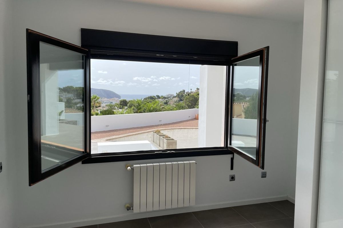 Kamer met grote open ramen, biedt uitzicht en natuurlijk licht in een villa in Moraira Teulada.