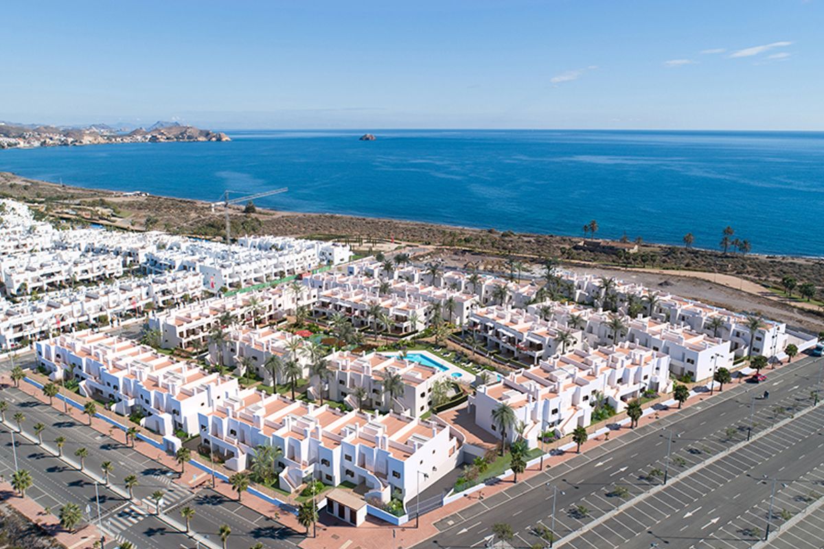 Luchtfoto van wit appartementencomplex aan de kust met blauwe zee en bergen in Mar de Pulpi, Spanje