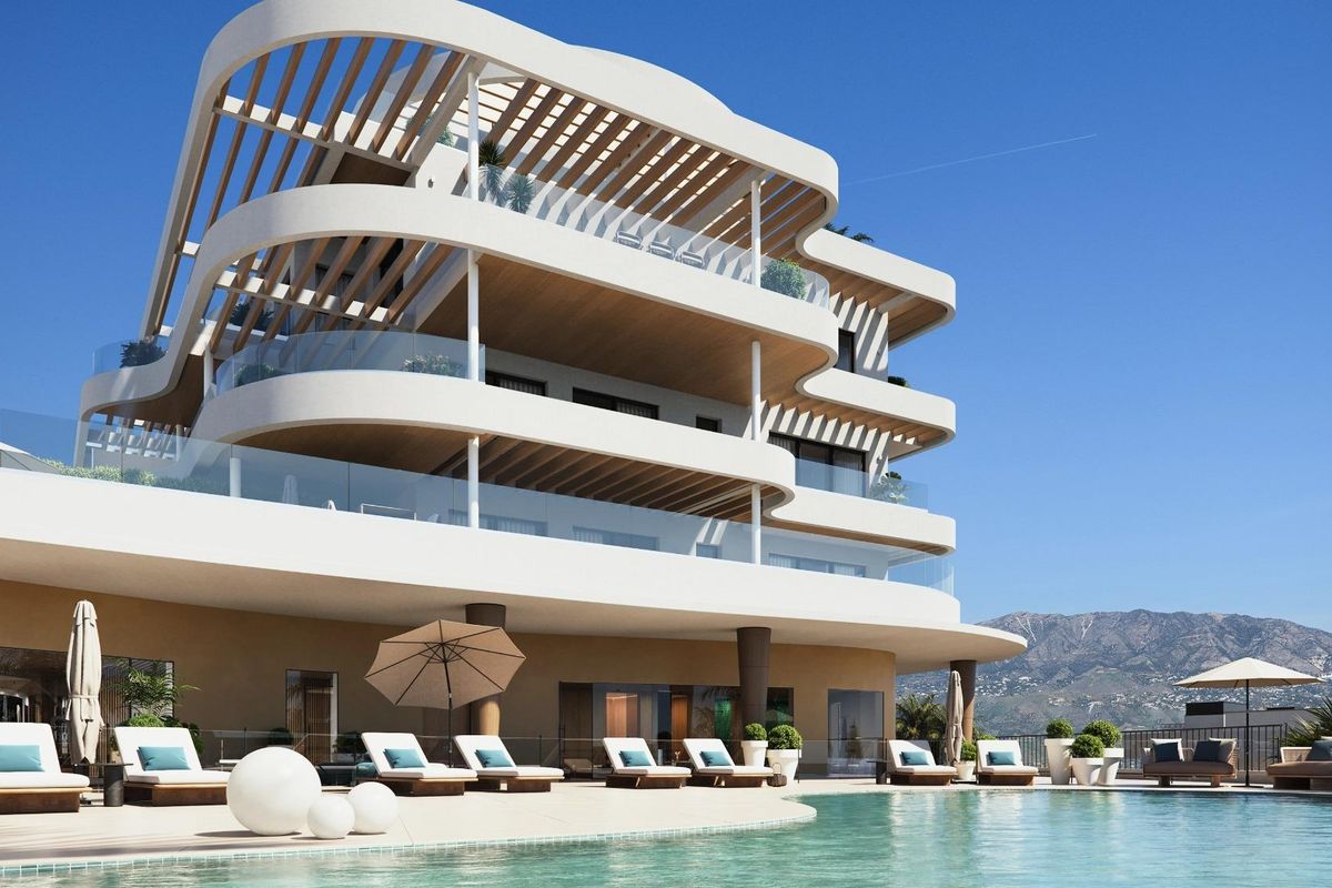Moderne zwembadgebied van een 3-slaapkamer appartement complex in Mijas, met ligstoelen en uitzicht op de bergen.
