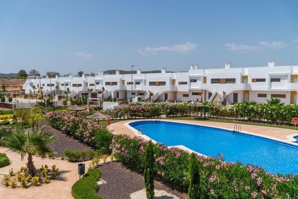 Een zonnig uitzicht op het gemeenschappelijke zwembad en de tuinen van een 2-slaapkamer appartement in Orihuela, Costa Blanca Zuid.