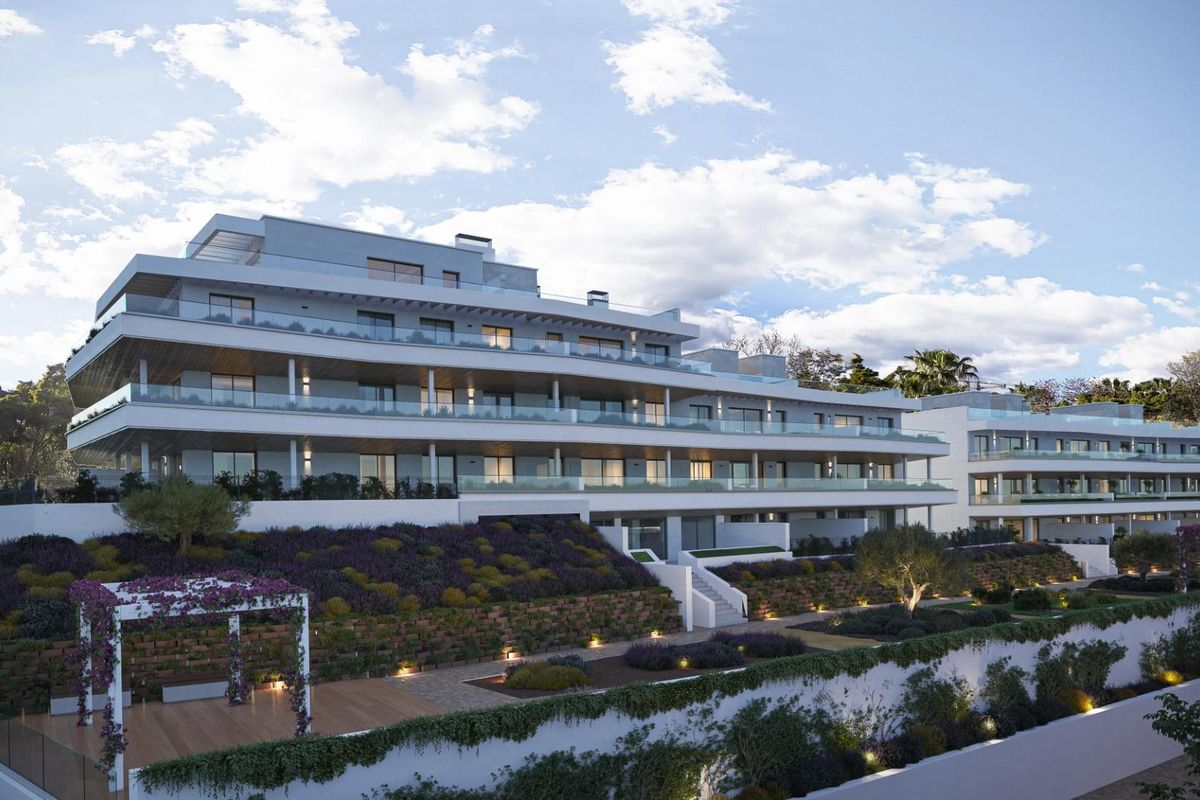 Gevel van moderne appartementen genesteld in het groen tegen een bewolkte lucht in Estepona, Costa del Sol, Spanje.