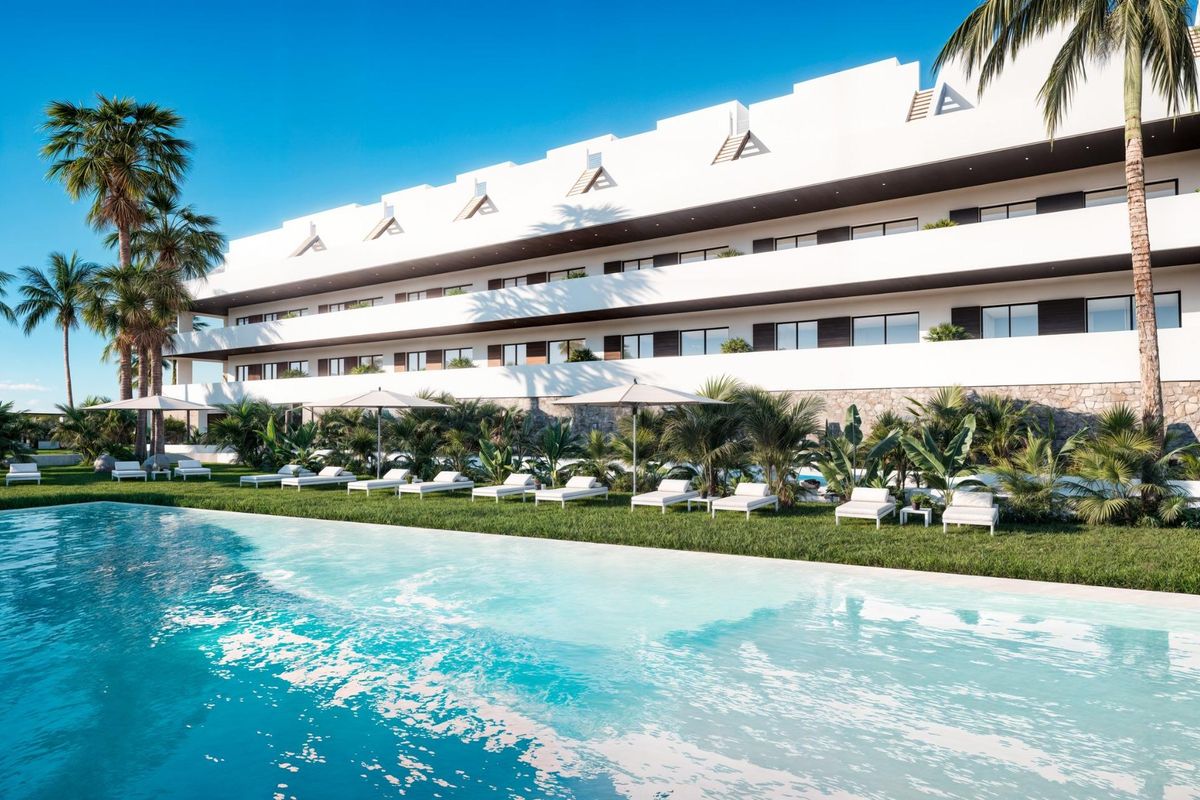 Zonnig uitzicht op het appartementencomplex in Finestrat, met een turquoise zwembad en ligstoelen.