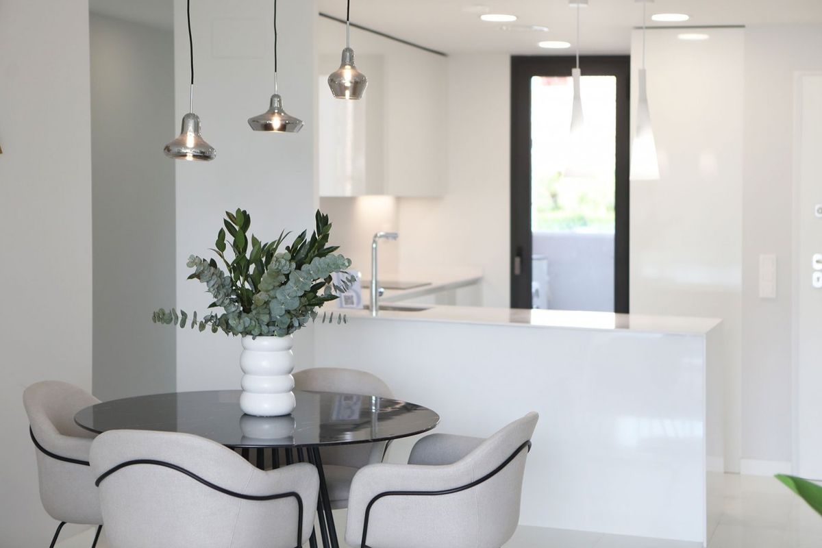 Eetgedeelte met een ronde tafel, moderne decoratie en uitzicht op de keuken in een appartement in Benidorm. 3 kamers.