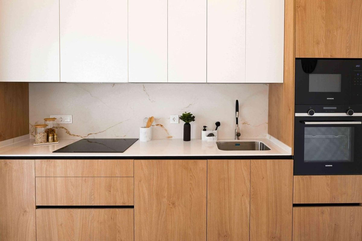 Moderne keukenopstelling met houten afwerkingen en inbouwapparatuur in een bungalow in Rojales.