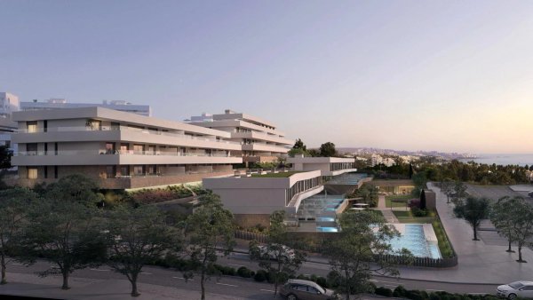 Buitenzijde van modern appartementencomplex in Estepona, met weelderige beplanting en een nabijgelegen zwembad.