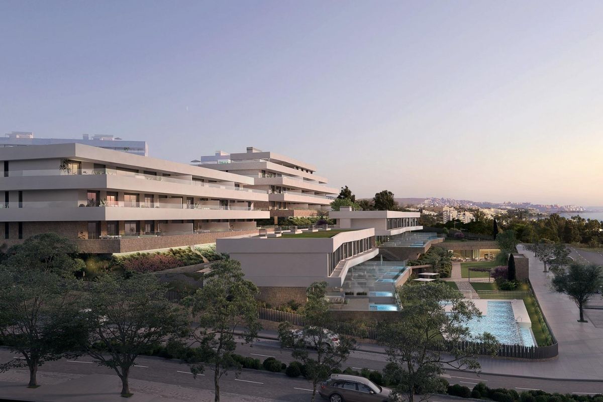 Buitenzijde van modern appartementencomplex in Estepona, met weelderige beplanting en een nabijgelegen zwembad.