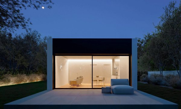 Exterieur van een moderne, minimalistische 1-slaapkamervilla in Alfas del Pi bij nacht. Grote glazen ramen onthullen het verlichte interieur.