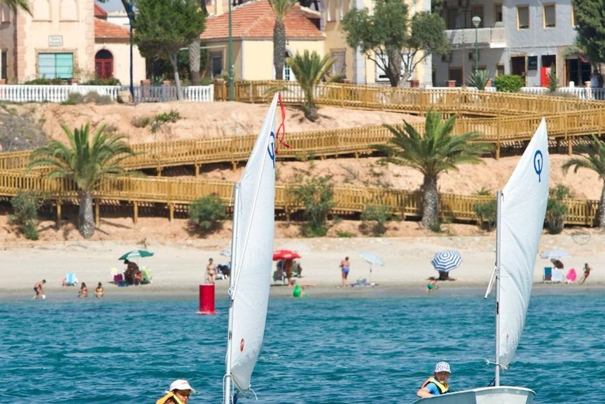 Zeilboten bij het strand met palmbomen en huizen in Pilar de La Horadada, Costa Blanca Zuid.