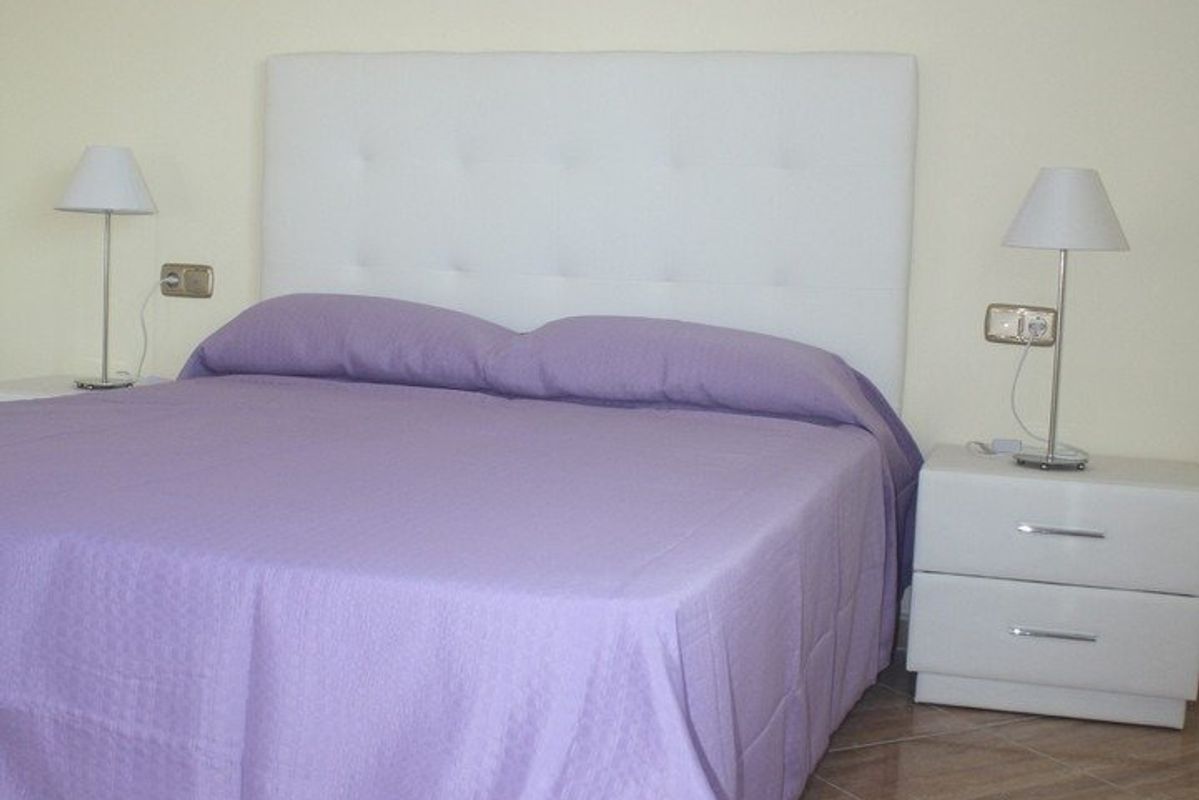 Stijlvolle paarse slaapkamer in de villa, ontworpen voor comfort en ontspanning met moderne nachtlampen.