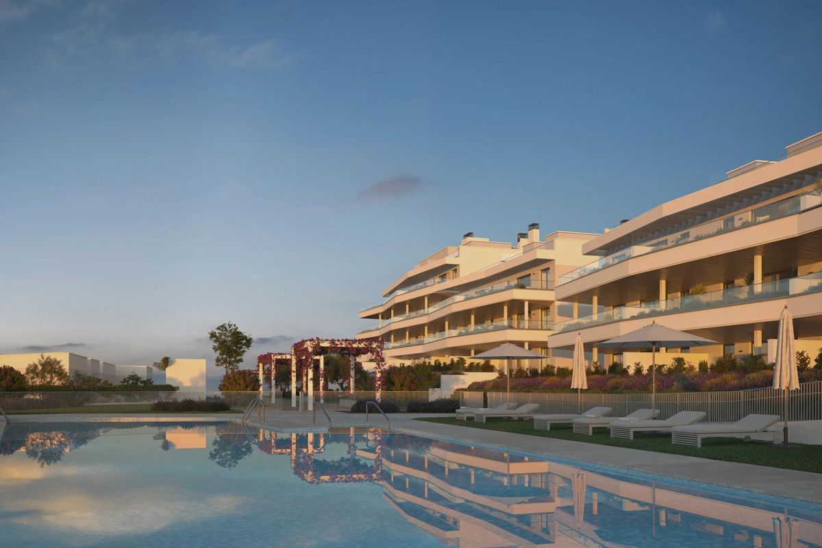 Buitenkant van een modern appartementencomplex in Estepona, reflecterend in het zwembad onder een heldere lucht.