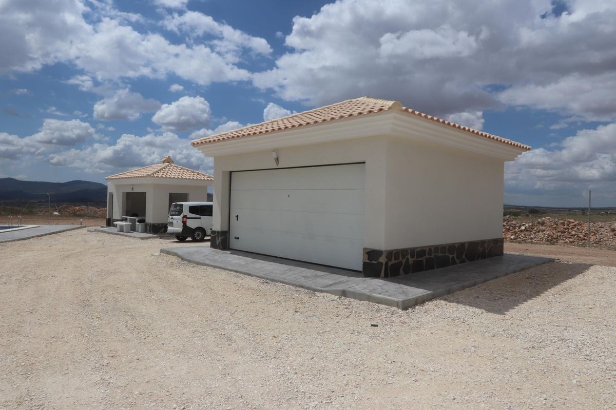 Twee garagegebouwen naast de villa in Pinoso, Spanje, ontworpen voor praktische opslag.