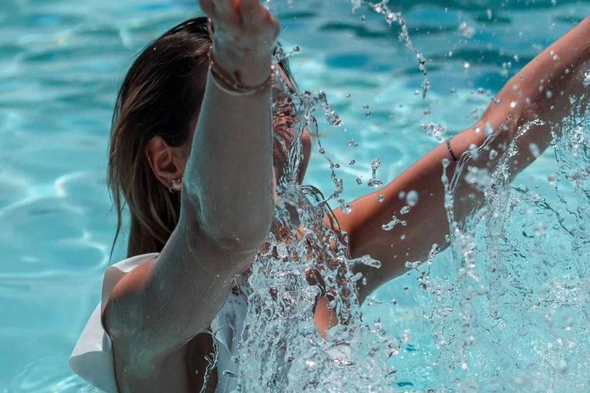 Een persoon die vrolijk water spat in een zwembad bij een flatgebouw in Mijas, Costa del Sol, Spanje.