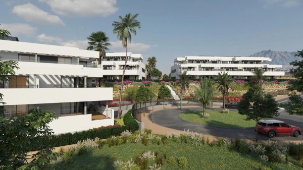 Buitenkant van een modern 2-slaapkamer penthouse complex in Casares, met groene tuinen en palmbomen.