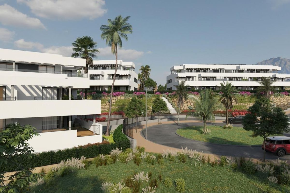 Buitenkant van een modern 2-slaapkamer penthouse complex in Casares, met groene tuinen en palmbomen.