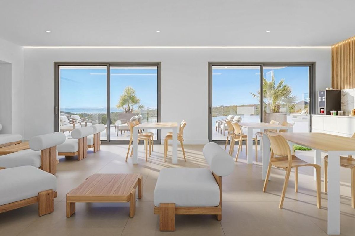 Heldere gemeenschappelijke lounge met moderne meubels en panoramische ramen in een appartementcomplex in Casares.