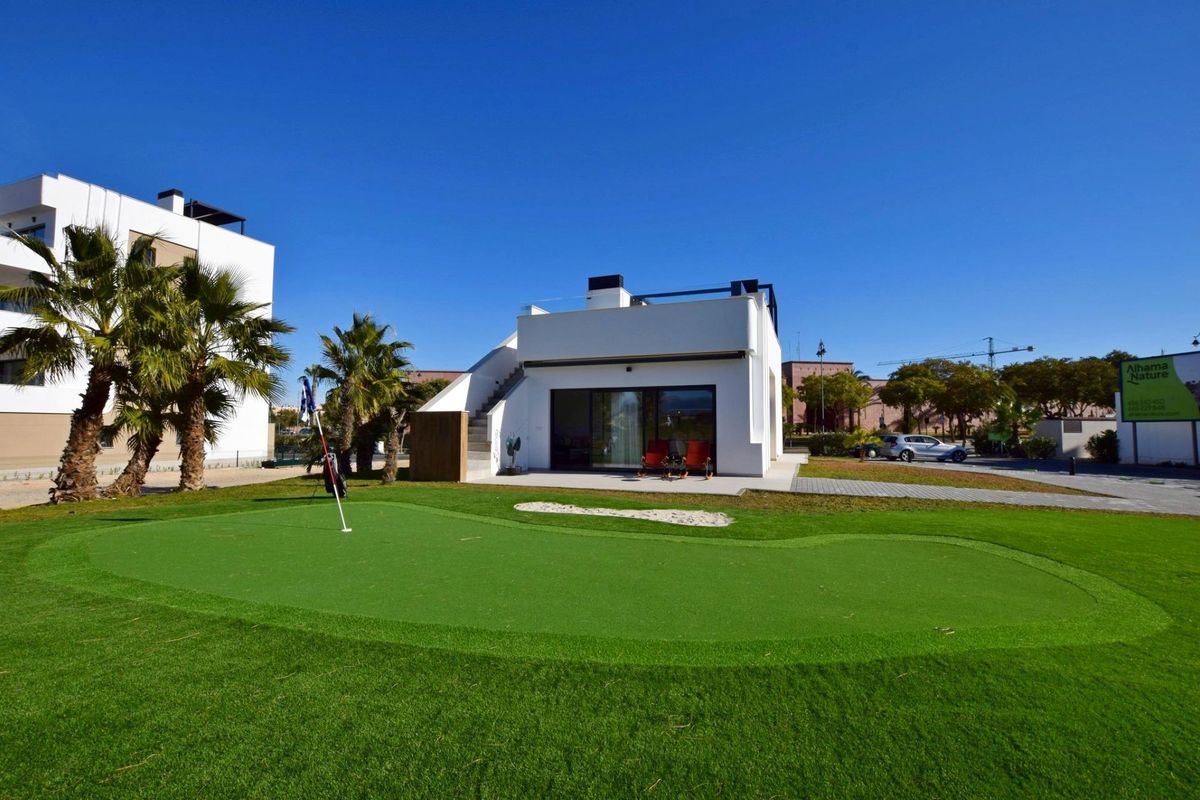 Buiten putting green en tuinzicht van een 3-slaapkamer villa in Alhama De Murcia onder fel zonlicht.