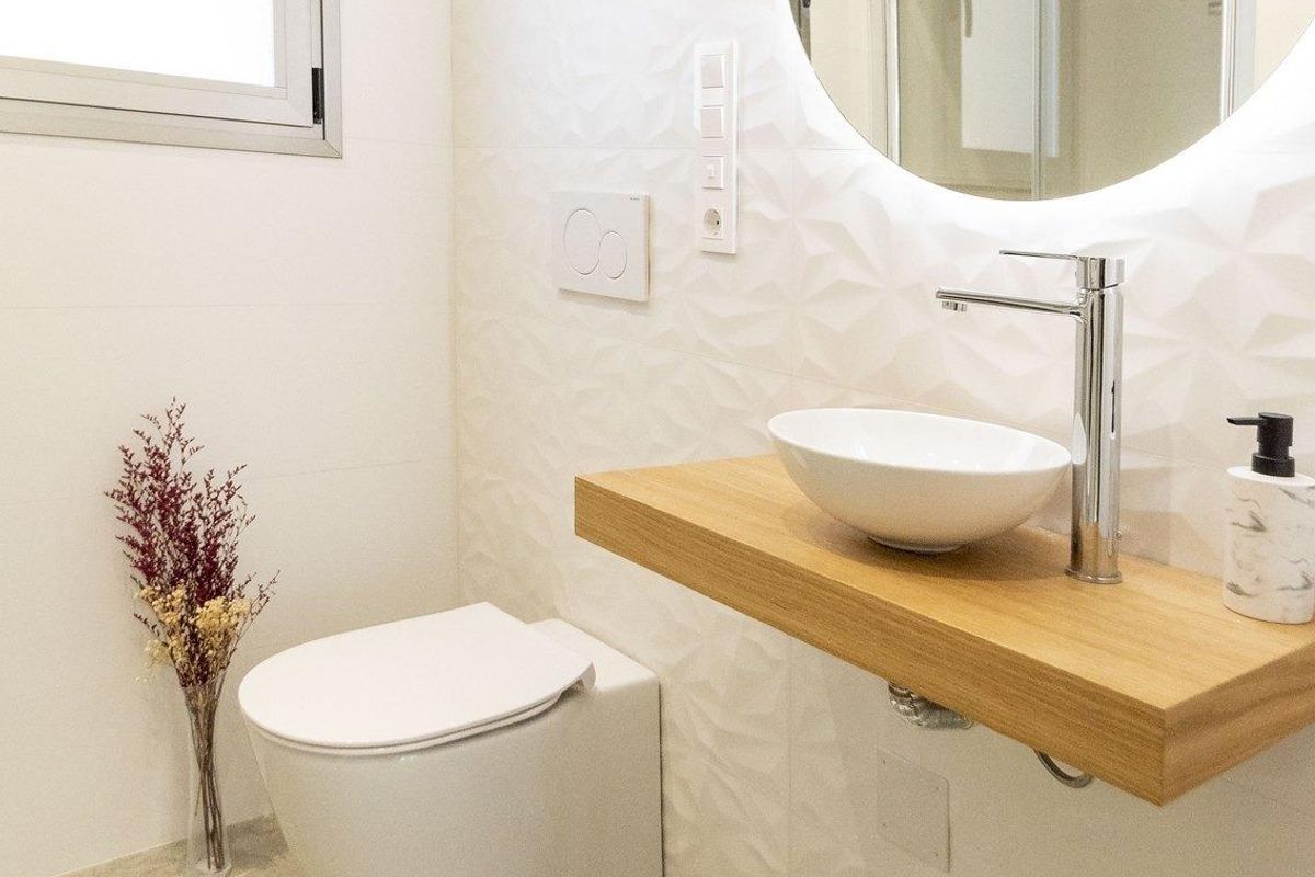 Een moderne badkamer met een ronde spiegel, wastafel en bloemen, in een 3-slaapkamer villa in Pilar de La Horadada.