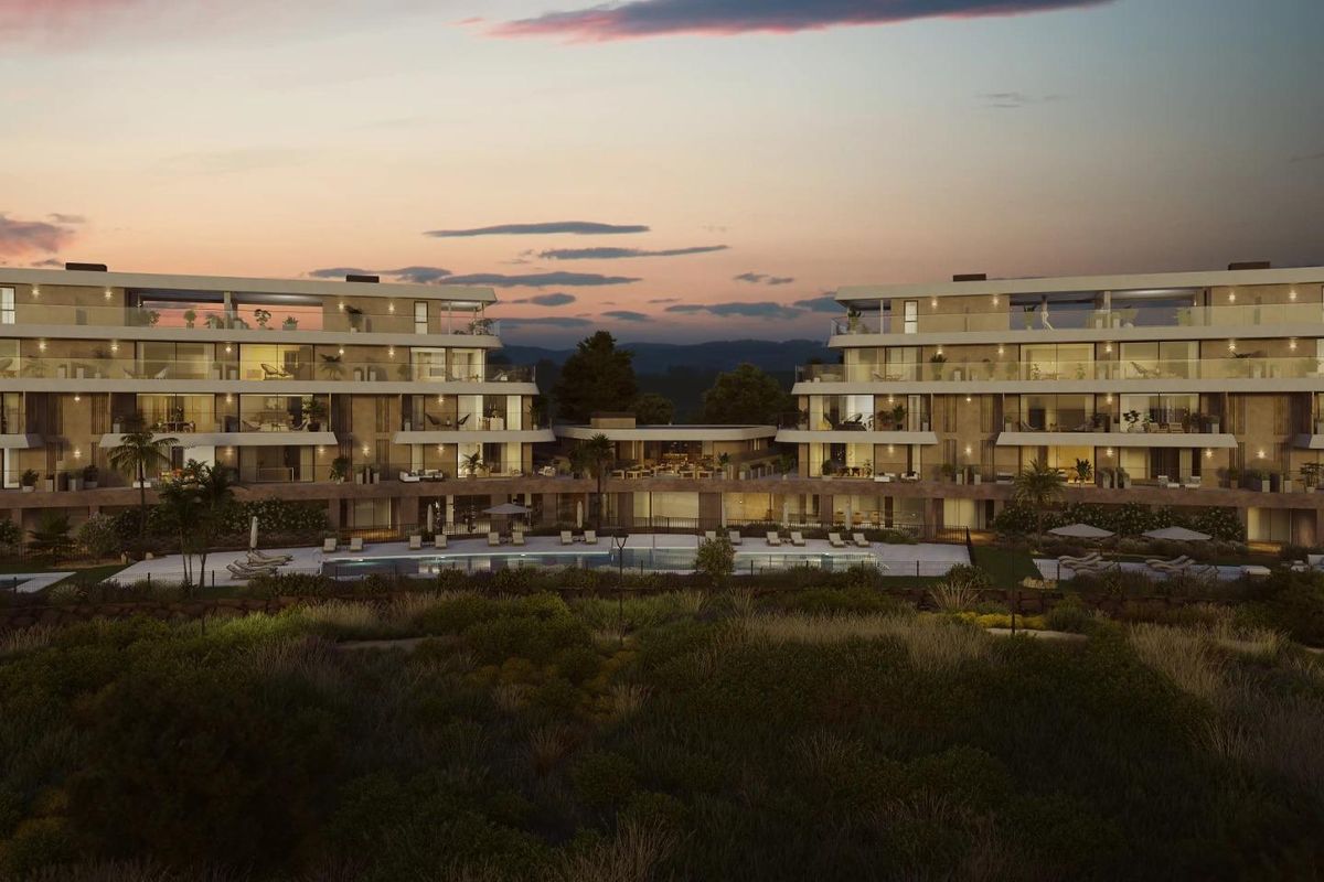 Avondzicht op het appartementencomplex in Estepona met verlichte balkons en buitenruimtes.