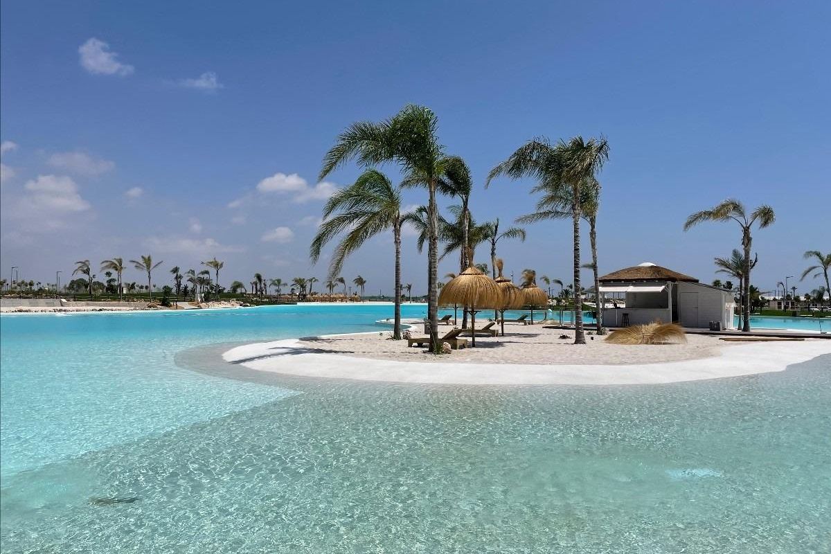 Rustige uitzicht langs het zwembad met palmbomen en zandstranden in Los Alcazares, uitnodigend tot ontspanning.