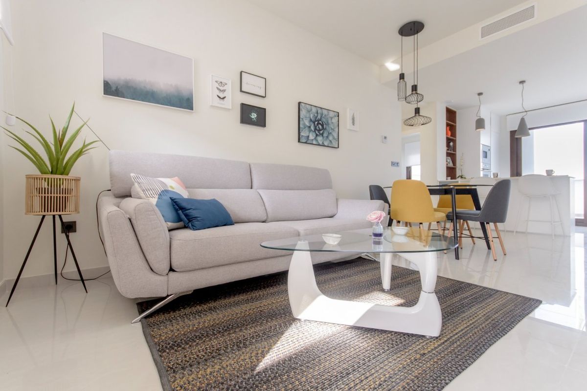 Stijlvolle hoek van de woonkamer met een grijze bank en een ronde salontafel in het appartement in Torrevieja.