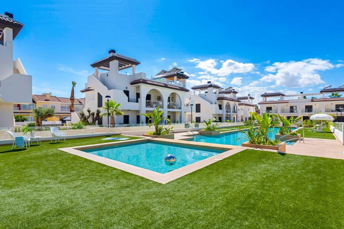 Buitenpool met ligstoelen en levendige beplanting in Rojales, Costa Blanca Zuid, Spanje.